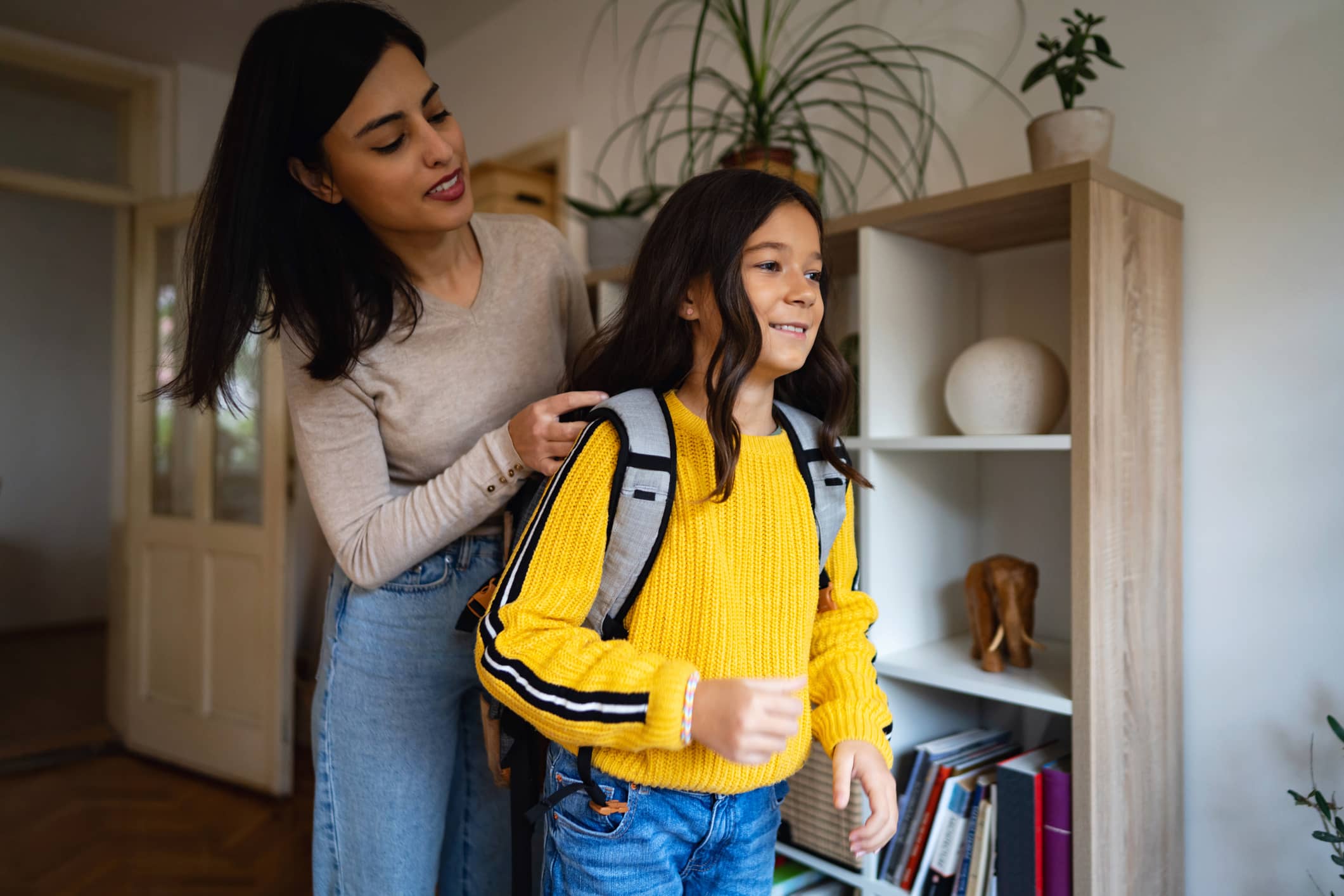 Mother helping child put on backpack